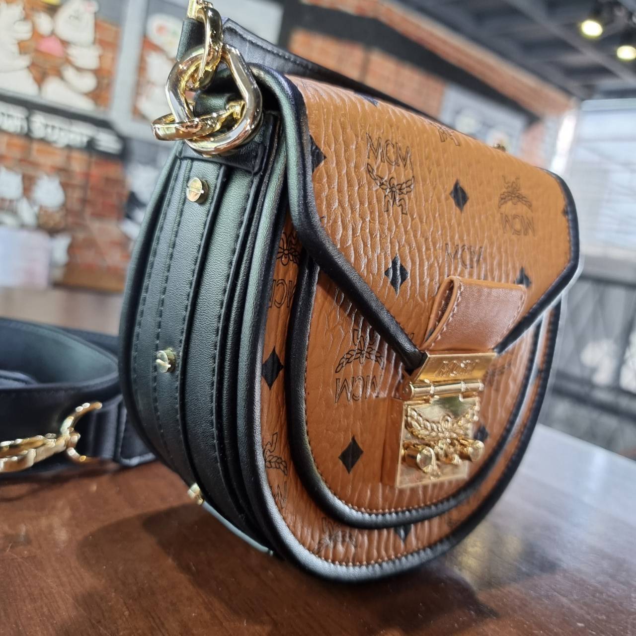 M.C.M MINI PATRICIA SHOULDER BAG IN VISETOS LEATHER BLOCK อัพเลเวลกระเป๋าของคุณด้วยไอเท็มนี้ไปเลยจ้า กระเป๋าสะพายทรง saddle ที่เก๋ไม่ซ้ำใคร ดีไซน์ขอบสีดำเพิ่มความยูนิค สวยสะดุดตา วัสดุหนังแคนวาสคุณภาพดี มาพร้อมสายสะพายหนังสีดำเรียบ และหูจับในตัว ทำให้ใช้ง