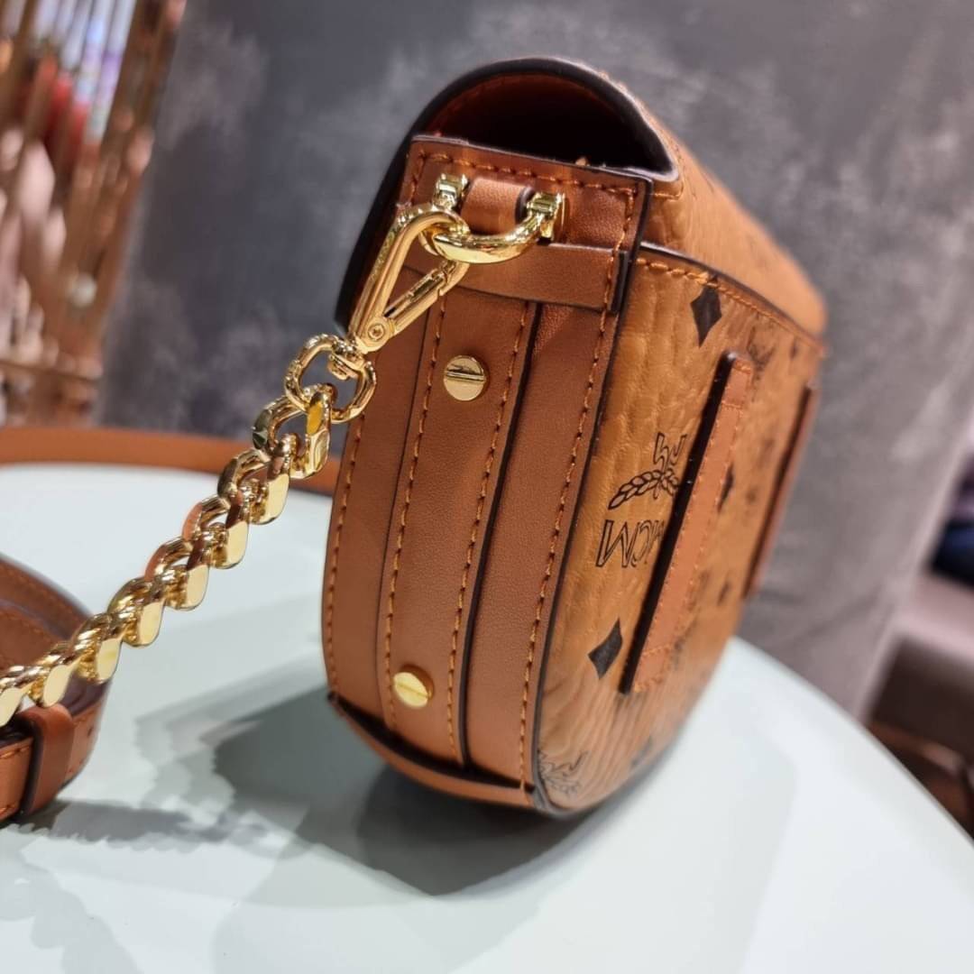 M.C.M MINI PATRICIA CROSSBODY IN VISETOS กระเป๋าสะพายไซส์มินิ แรงดีไม่มีตกน้า คอลเลคชั่นนี้ดีไซน์แปลกใหม่ ทรงโค้งมน สวยหรู ด้านข้างตกแต่งหมุดทองรอบใบ วัสดุตัวกระเป๋าเป็นหนังแคนวาสคุณภาพดี ภายในเป็นหนังกลับสีส้มโดดเด่นเป็นเอกลักษณ์ มีช่องใส่บัตรแยกให้ เปิด