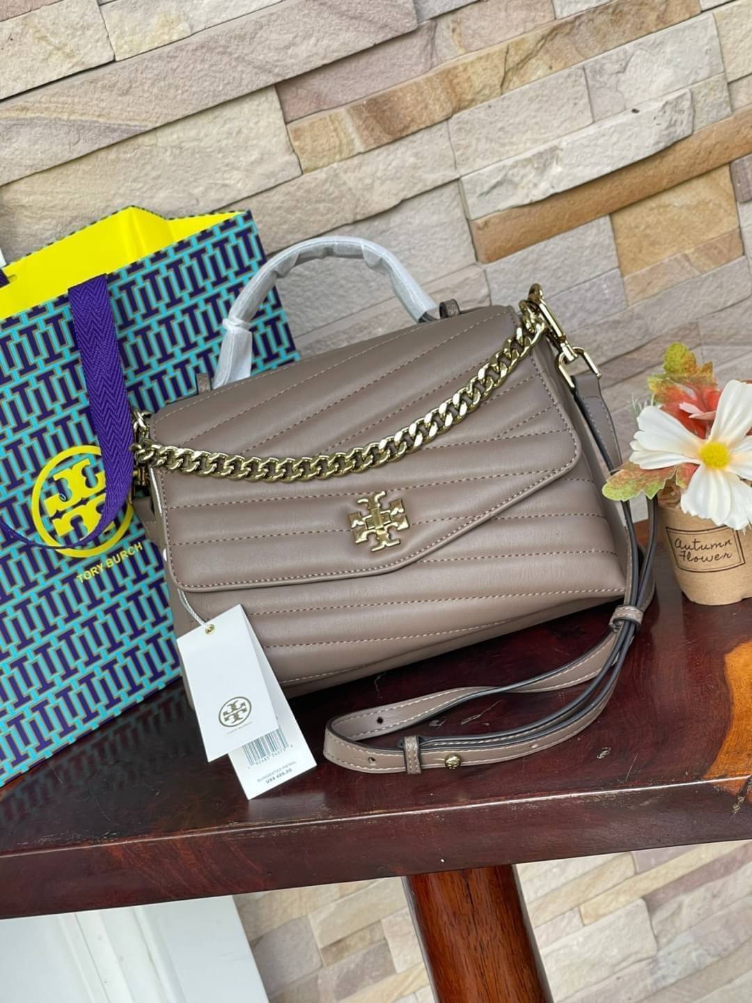 TORY BURCH Kira Chevron Top-handle Satchel กระเป๋าหนังแกะ สัมผัสนุ่มควบคู่กับดีไซน์อันเป็นเอกลักษณ์ กระเป๋าถือทรงสวยที่มีดีไซน์อันเป็นเอกลักษณ์ไม่เหมือนกับที่ไหน ด้วยการตัดเย็บหนังแกะแสนนุ่มแบบลายบุสองชั้น เพิ่มมูลค่าด้วยสายสะพายที่ทำจากโลหะสีทอง อีกทั้งย