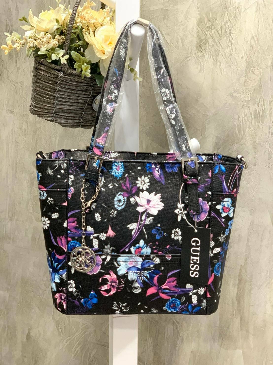 GUESS Women's Medium Floral Tote Bag กระเป๋าถือ คล้องไหล่หรือสะพาย ขนาดกลาง วัสดุหนังpu ลายดอกไม้ชนิดต่างๆรอบใบ เปิดปิดใช้งานด้วยซิปเดียวด้านบน ภายในมีกว้างใส่กระเป๋าสตาวค์ยาว มินิไอแพคได้ หูจับและสายสะพายปรับระดับได้ มาพร้อมกุญแจโลโก้guess สวยน่ารัก