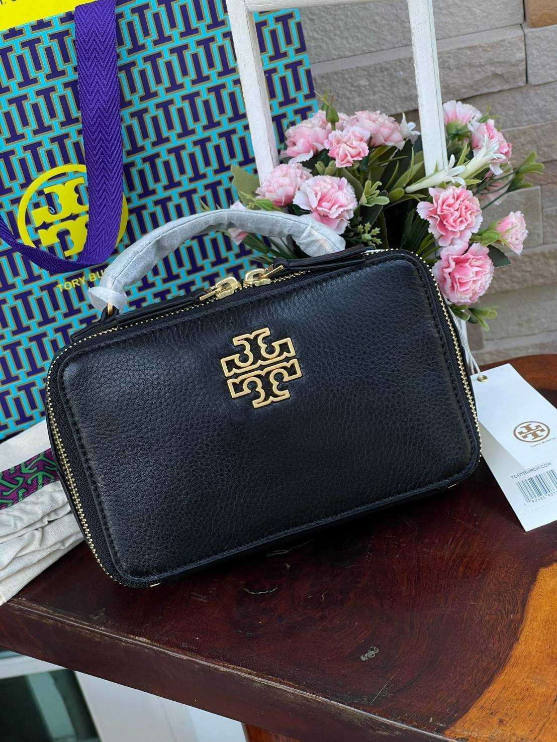 Tory burch Top Handle Case (84710) Collection ใหม่ที่เพิ่งเปิดตัวไปไม่นานจุดเด่นของรุ่นนี้คือดีไซน์ออกมาในสไตล์คลาสสิกที่มาพร้อมกับฮาร์ดแวร์ที่ทำจากวัสดุทองเหลืองและสายสะพายโซ่และหนัง ปากกระเป๋าเปิดได้กว้างแบบสองซิป รูปทรงสามารถสะพายใช้งานได้หลายโอกาส ไม่