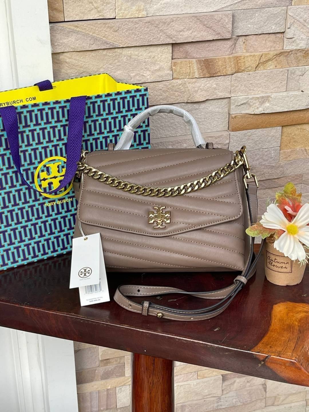 TORY BURCH Kira Chevron Top-handle Satchel กระเป๋าหนังแกะ สัมผัสนุ่มควบคู่กับดีไซน์อันเป็นเอกลักษณ์ กระเป๋าถือทรงสวยที่มีดีไซน์อันเป็นเอกลักษณ์ไม่เหมือนกับที่ไหน ด้วยการตัดเย็บหนังแกะแสนนุ่มแบบลายบุสองชั้น เพิ่มมูลค่าด้วยสายสะพายที่ทำจากโลหะสีทอง อีกทั้งย