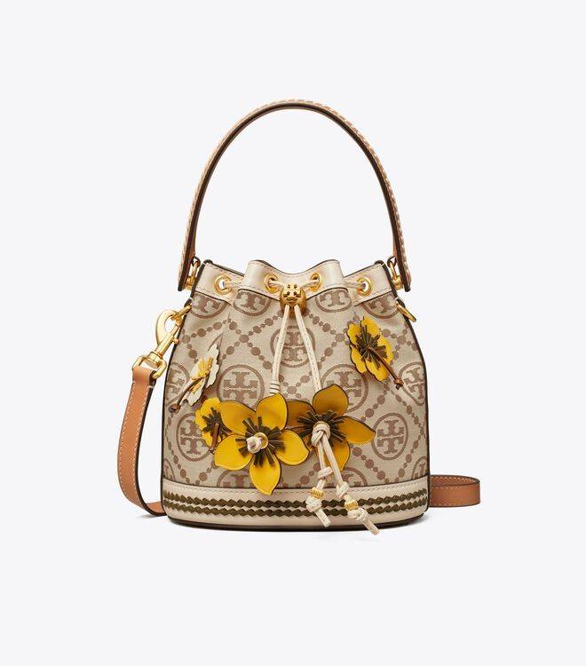 TORY BURCH T MONOGRAM FLORAL BUCKET BAG คอลเลคชั่นใหม่ พร้อมเสิร์ฟความสวยให้ถึงบ้าน!! กระเป๋าบัคเก็ตทรงยอดนิยม ดีไซน์ใหม่ล่าสุด สไตล์งานคราฟ มีลูกเล่นประดับดอกไม้กับตัวกระเป๋า และตัวรูดสาย วัสดุผ้า jacquard ตัดสลับหนังแท้ หูจับและขอบกระเป๋าตกแต่งลายสานสวย