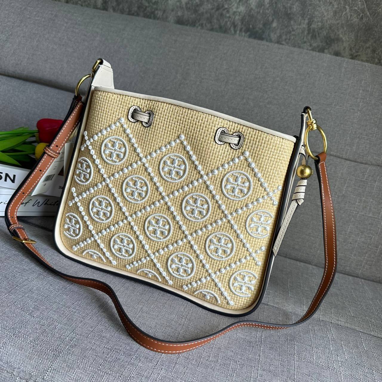 TORY BURCH T Monogram Straw Bell Bag กระเป๋าสะพายข้างรุ่นคลาสสิกที่ได้แรงบันดาลใจจากการควิลท์แบบดั้งเดิมของเพนซิลเวเนีย คอลเลกชันบ่งบอกถึงความมีสไตล์เหนือกาลเวลา รูปทรงเรียวโดดเด่น ปักทอลายแบรนด์อย่างสวยงาม เปิด ปิดด้วยเชือกรูด ด้านในช่องโล่งกว้าง ซับในผ้