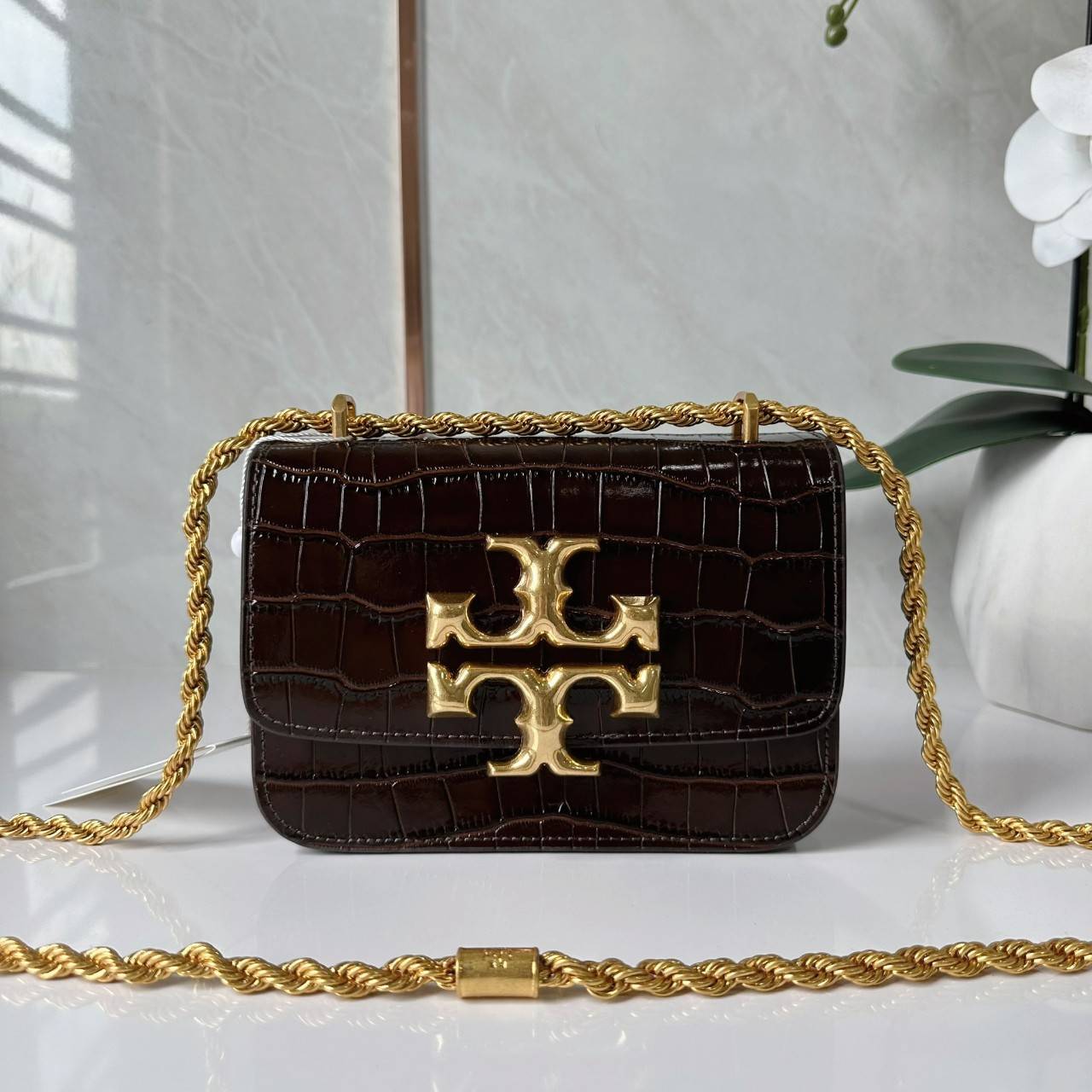 6 สี Tory Burch Croc Eleanor Small Bag / TORY BURCH ELEANOR CROC EMBOSSED LEATHER กระเป๋าสะพายหนังพิมพ์ลายจระเข้ ดีไซน์หรูหรา โด่นเด่นด้วยโลโก้แบรนด์อะไหล่ด้านหน้า และสายสะพายโลหะสีทอง