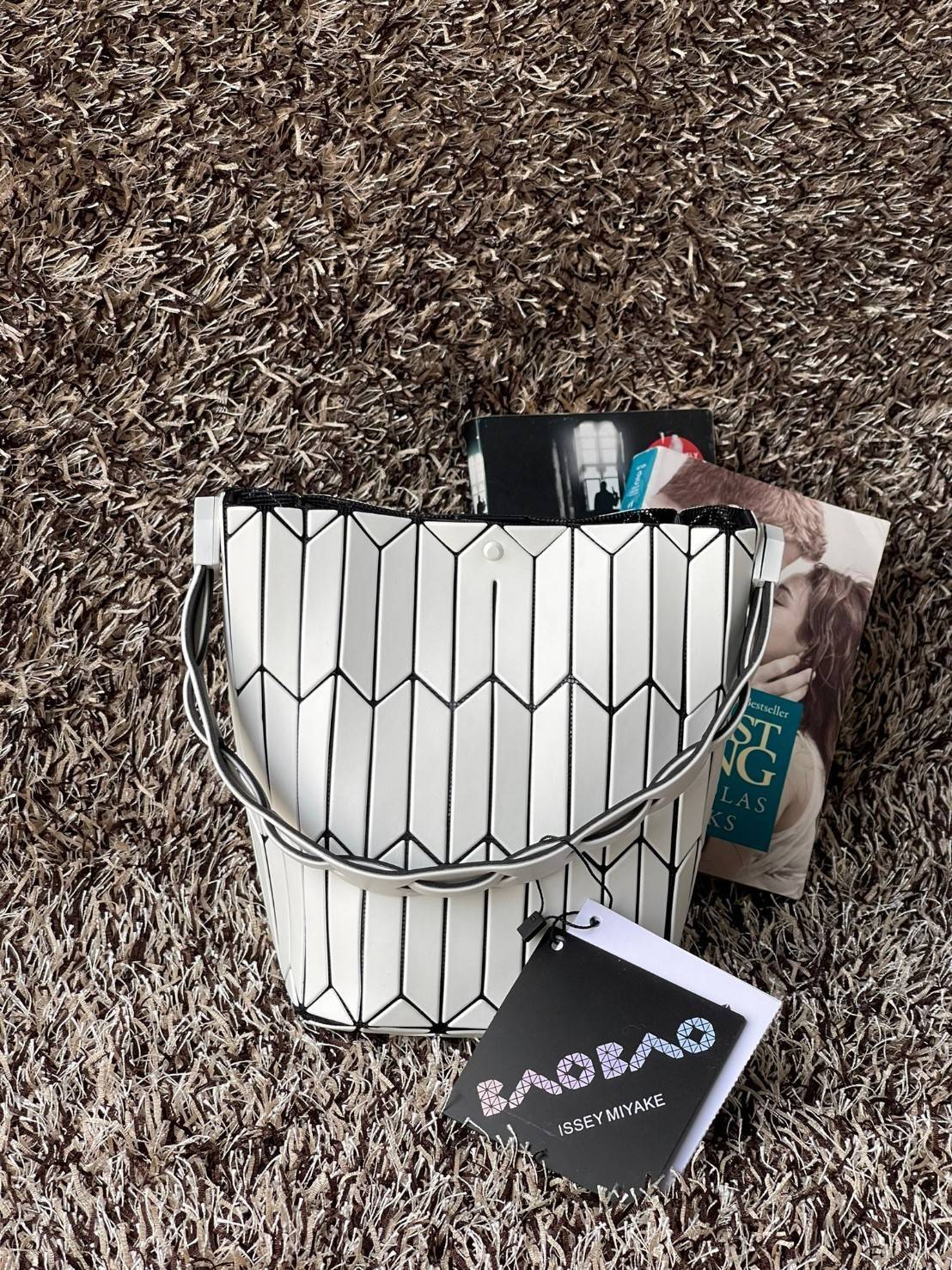 Small : BAO BAO ISSEY MIYAKE SMALL BUCKET เป็นกระเป๋าบัคเก็ตขนาดเล็กสามารถใช้ใส่กระเป๋าสตางค์และโทรศัพท์มือถือได้ ซีรีย์ใหม่นี้มีจุดเด่นที่แผ่นรูปทรงสี่เหลี่ยมด้านขนานในแนวตั้ง เกิดเป็นรูปทรงสามมิติซึ่งแตกต่างไปจากรูปทรงที่เกิดขึ้นจากแผ่นสามเหลี่ยม หูหิ้ว