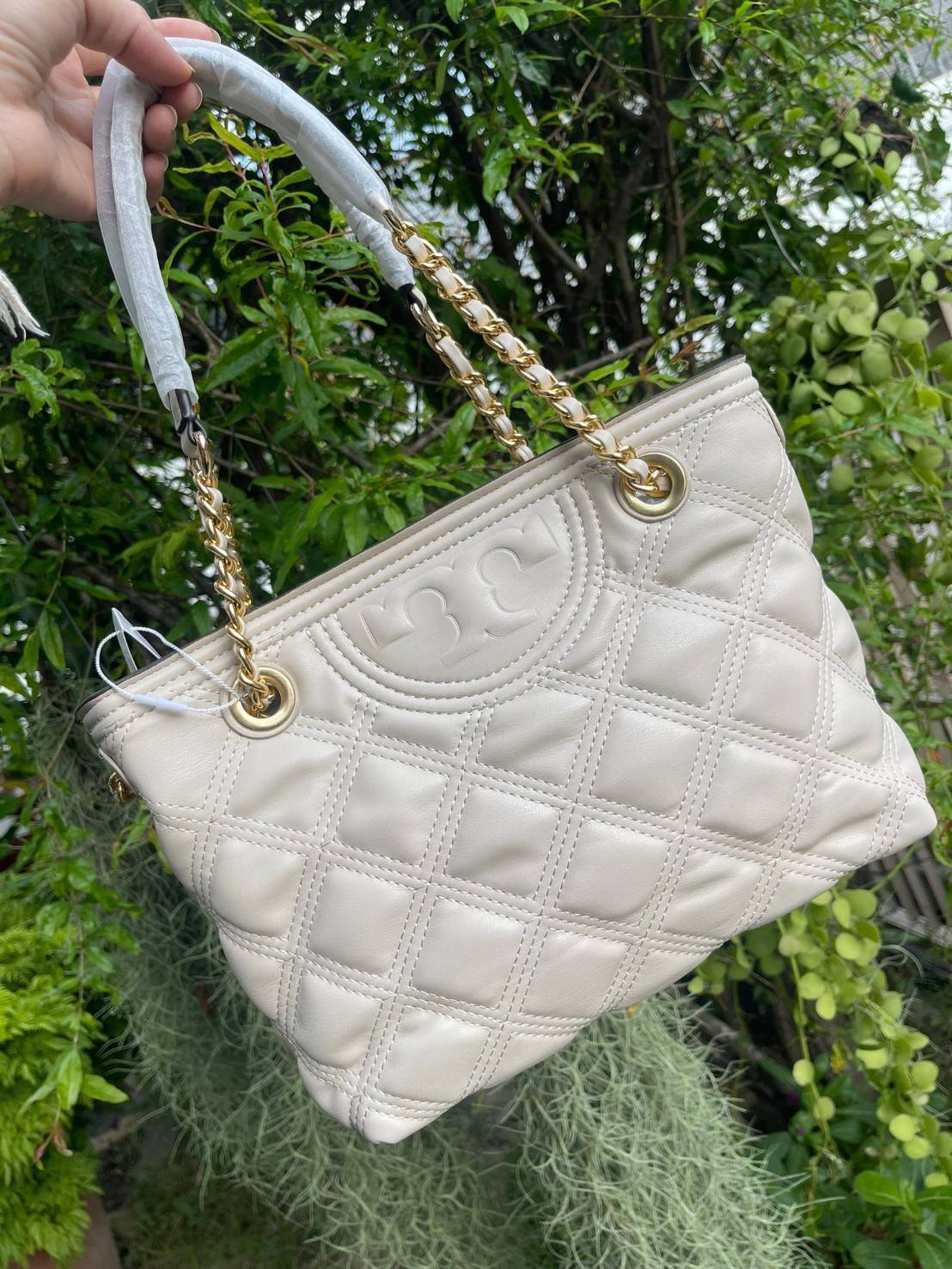 Tory Burch Fleming Soft Small Tote Bag เป็นกระเป๋าสะพายไหล่น่ารัก ๆ สักใบที่มีดีไซน์โดดเด่น สะดุดตา ใน Collection เรียกได้ว่าขายดีอันดับต้น ๆ ของแบรนด์ ใช้ได้ในลุคช์ทางการและกึ่งทางการ ดีเทลการตัดเย็บพิมพ์ลายนูนคู่กับแพทเทิร์นสี่เหลี่ยมทรงเพชร ที่ช่วยเพิ่