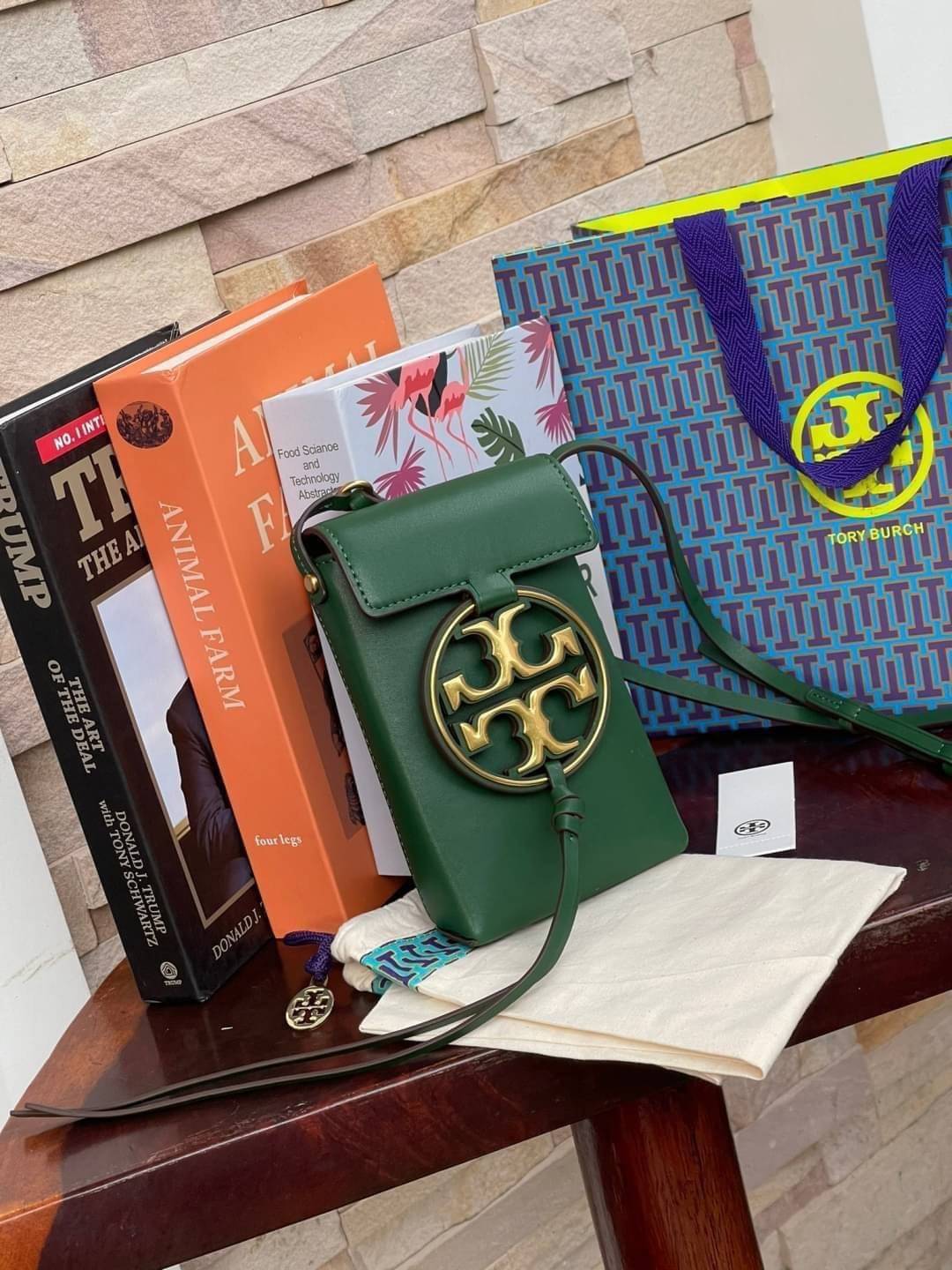 TORY BURCH MILLER METAL PHONE CROSSBODY อีกหนึ่งกระเป๋าใส่มือถือรุ่นฮิตที่เชื่อว่าหลาย ๆ คนต้องเคยเห็นผ่าน ๆ ตามาอย่างแน่นอน กับแบรนด์ Tory Burch ดีไซน์กระเป๋าทรงฝาพับแม่เหล็กใช้งานง่าย มาพร้อมดีเทล Logo แบรนด์โดดเด่นสีทองตัดกับหนังแกะสีดำ ดูหรูดูแพง! แต่