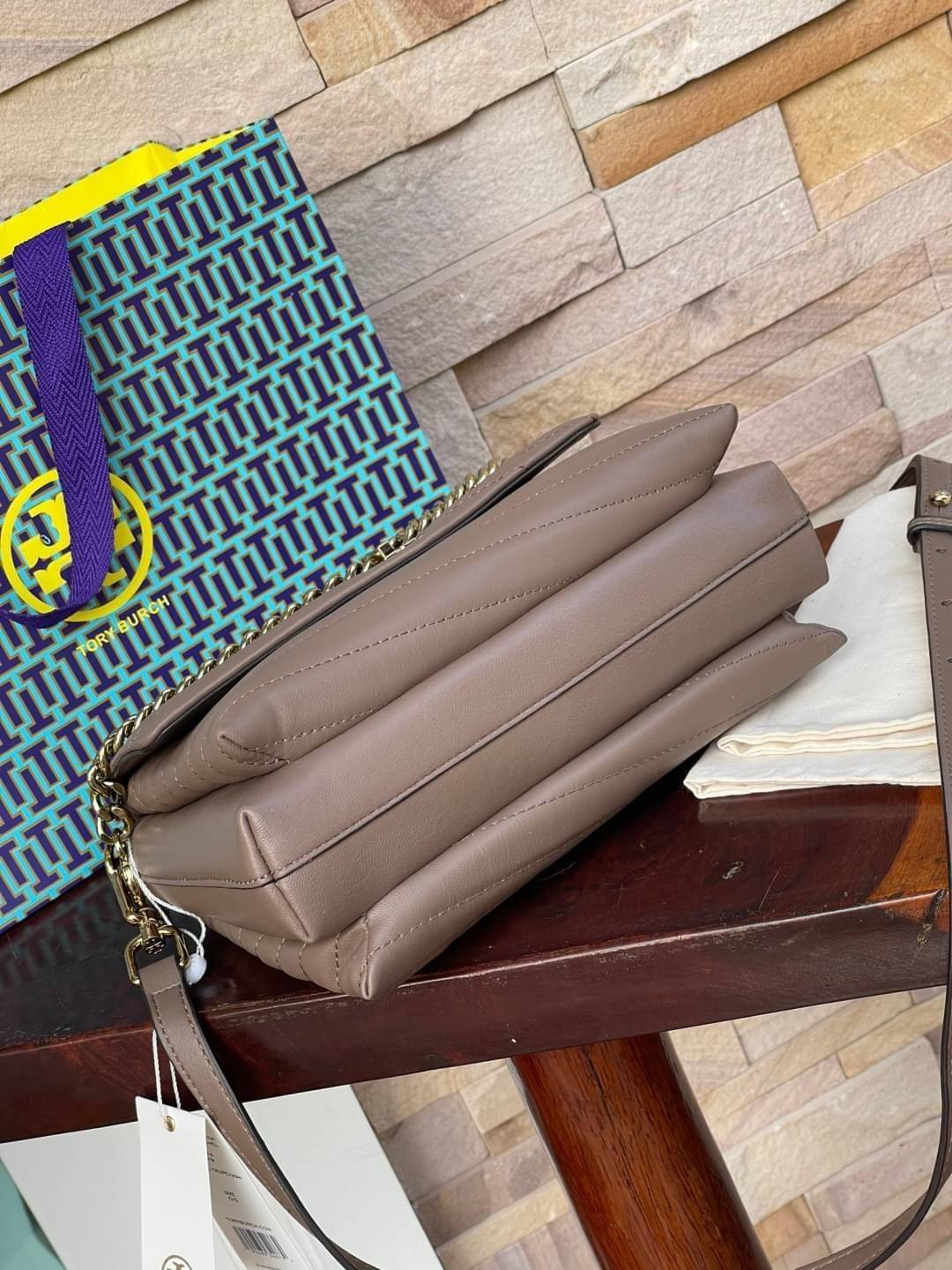 TORY BURCH Kira Chevron Top-handle Satchel กระเป๋าหนังแกะ สัมผัสนุ่มควบคู่กับดีไซน์อันเป็นเอกลักษณ์ กระเป๋าถือทรงสวยที่มีดีไซน์อันเป็นเอกลักษณ์ไม่เหมือนกับที่ไหน ด้วยการตัดเย็บหนังแกะแสนนุ่มแบบลายบุสองชั้น เพิ่มมูลค่าด้วยสายสะพายที่ทำจากโลหะสีทอง อีกทั้งย