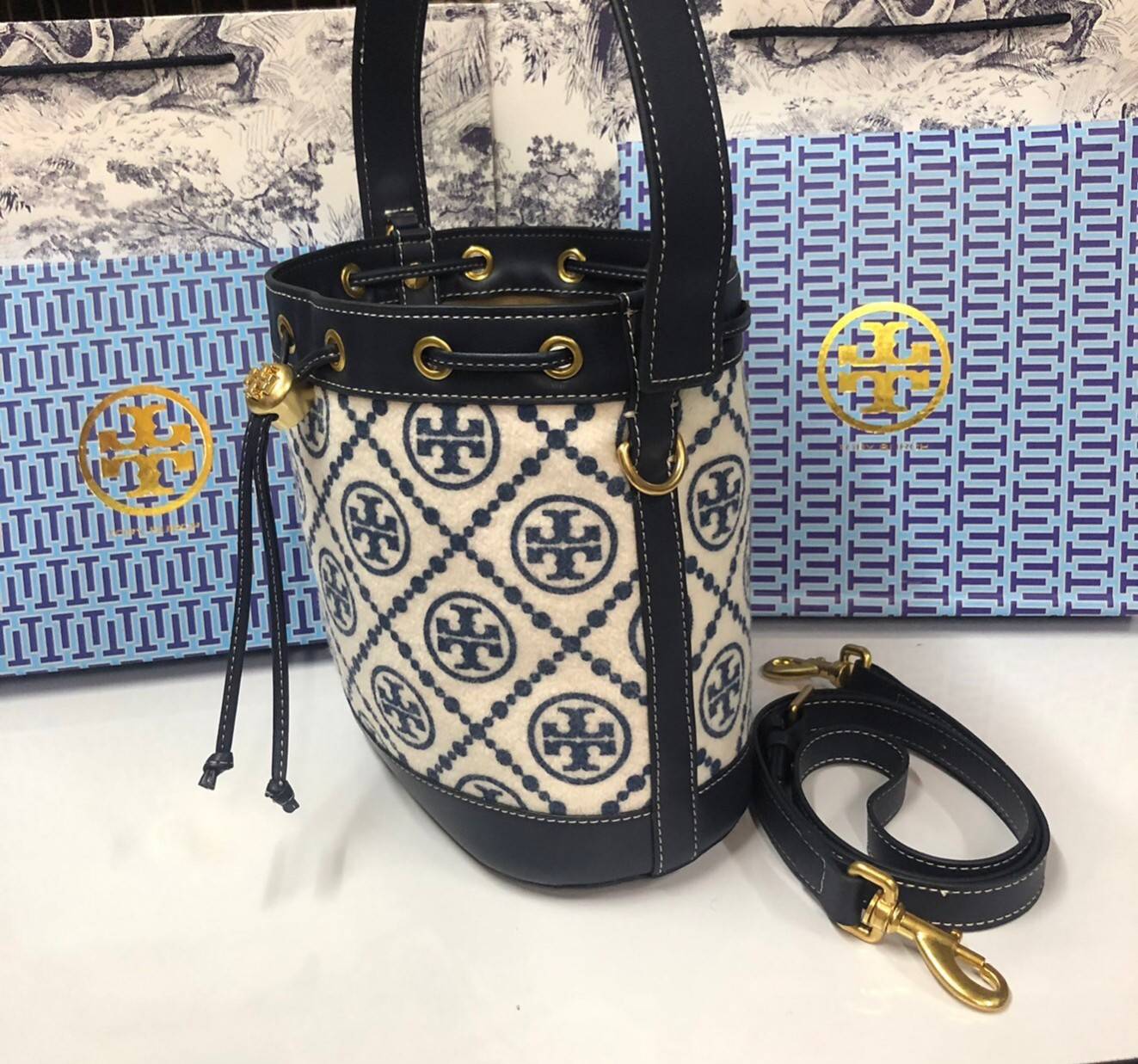 Medium : Tory Burch T Monogram Chenille Bucket Bag เปิดตัวอีกหนึ่งรุ่นกับกระเป๋าลาย T MONOGRAM รุ่นใหม่ล่าสุดจาก TORY BURCH พลาดไม่ได้กับโลโก้สุดคลาสสิก ลวดลาย T Monogram คือวัสดุ chenille หรือที่เรียกว่า ด้านไหมกำมะหยี่ มารังสรรค์ลงบนกระเป๋าBucketใบนี้ เ