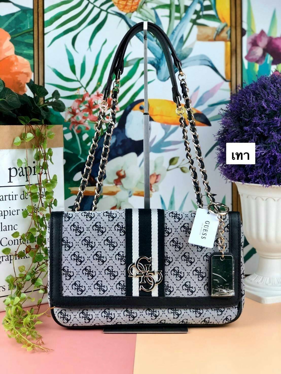 Guess Logo city handbag กระเป๋าสะพายไหล่ ตัวกระเป๋าเป็นผ้าลาย signature ของแบรนด์ ตัดกับหนังที่ตัวขอบกระเป๋า มาพร้อมพวงกุญแจโลโก้แบรนด์ ด้านหน้ามีโลโก้แบรนด์ ด้านหลังมีช่องใส่โทรศัพท์/บัตรได้ เปิดปิดแบบกระดุมแม่เหล็กซ้าย-ขวา ด้านในมีช่องซิป เล็ก 1 ช่อง แล