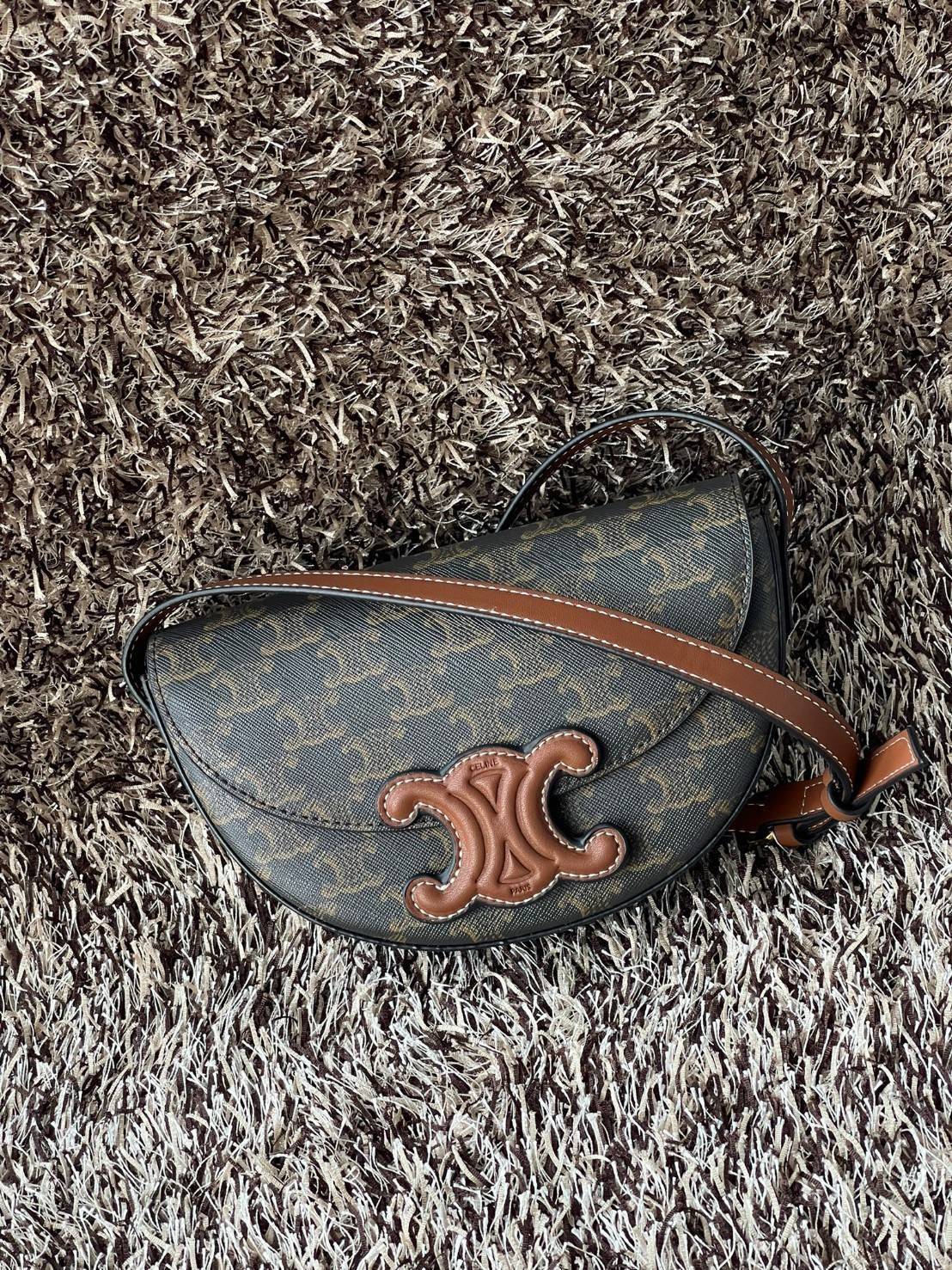 CELINE BESACE CUIR TRIOMPHE IN SMOOTH กระเป๋ารุ่นนี้นำเสนอในรูปทรงฮาล์ฟมูนที่ตอนนี้กำลังงมาแรง เปิดด้วยกระดุมแป๊กเพื่อเผยให้เห็นช่องภายในที่กว้างขวางและกระเป๋าด้านในแบบแบน คุณสมบัติที่โดดเด่นอีกอย่างของกระเป๋าอยู่ที่โลโก้ขนาดใหญ่ รูปทรงสะดุดตา สามารถสะพาย