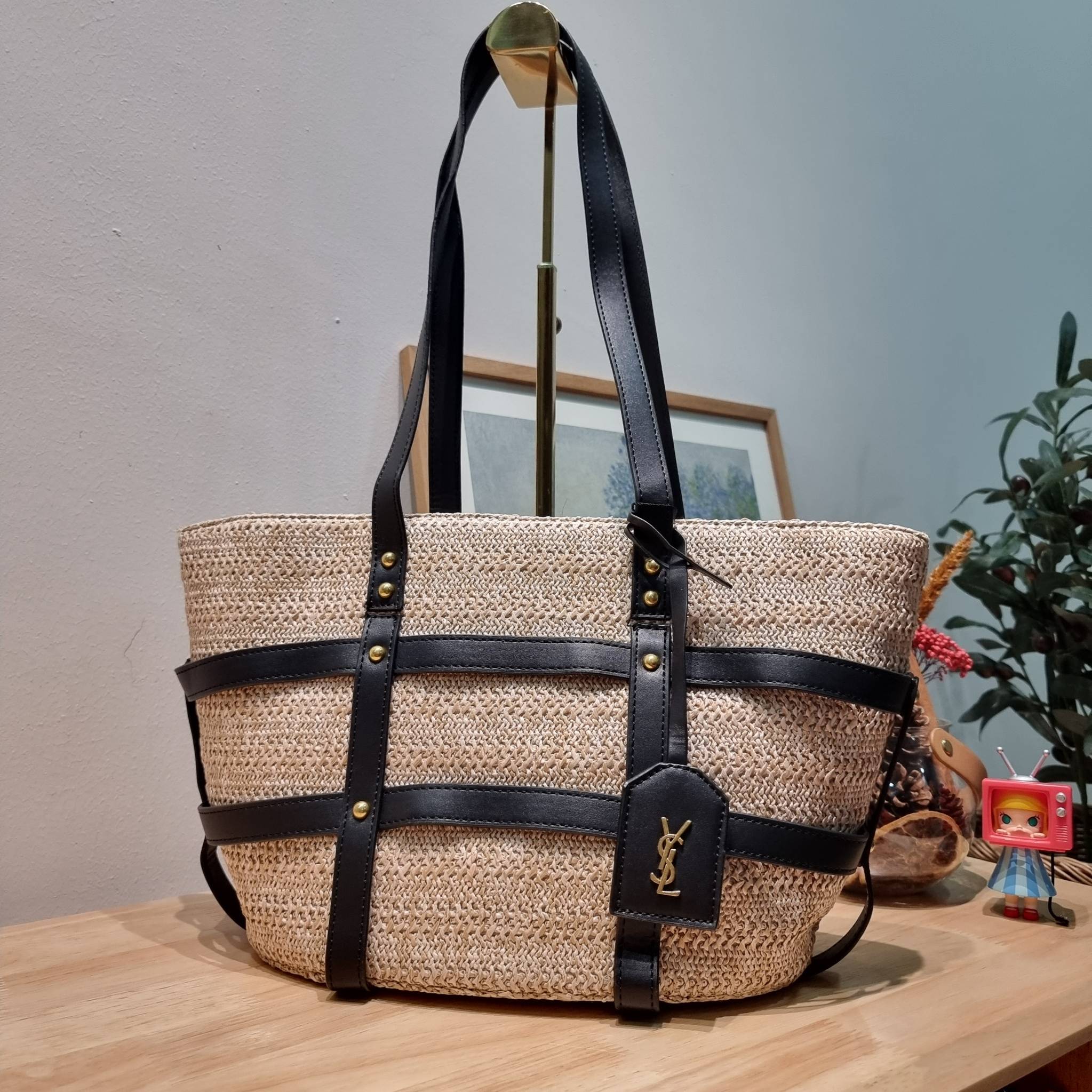 YSL PANIER STUDDED LEATHER TRIMMED WOVEN RAFFIA สวยไม่ซ้ำใคร ใหม่ที่สุด กับกระเป๋าสะพายสานทรงยูนีค ที่เติมดีเทลความหรูด้วยสายหนังคาดตกแต่ง ดูแพงไปอีก