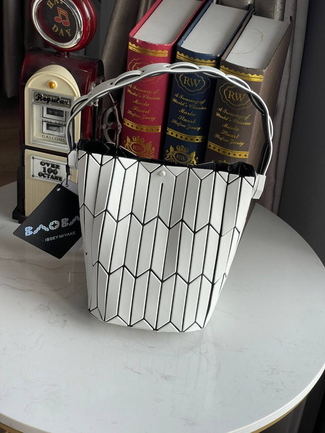 Small : BAO BAO ISSEY MIYAKE SMALL BUCKET เป็นกระเป๋าบัคเก็ตขนาดเล็กสามารถใช้ใส่กระเป๋าสตางค์และโทรศัพท์มือถือได้ ซีรีย์ใหม่นี้มีจุดเด่นที่แผ่นรูปทรงสี่เหลี่ยมด้านขนานในแนวตั้ง เกิดเป็นรูปทรงสามมิติซึ่งแตกต่างไปจากรูปทรงที่เกิดขึ้นจากแผ่นสามเหลี่ยม หูหิ้ว