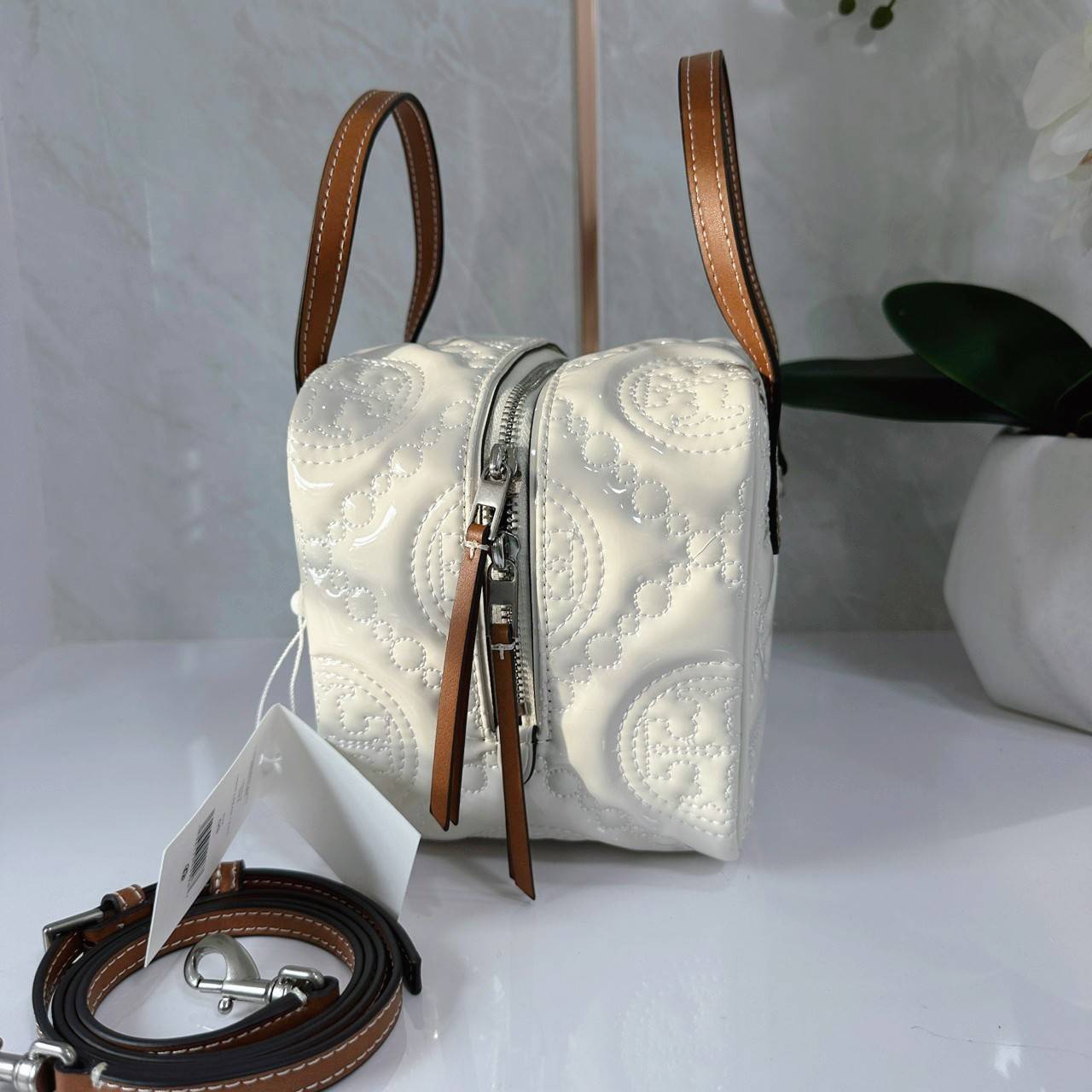 Tory Burch T Monogram Embroidered Patent Cube คอลเลคชั่นใหม่ รุ่นลิมิเต็ดรูปทรงใหม่ T Monogram สุดcube วัสดุหนังแท้ เปิด-ปิดด้วยซิป ภายในกว้าง มีช่องแยก 1 ช่อง สามารถใส่โทรศัพท์มือถือได้ทุกรุ่น สามารถถือหิ้วหรือสะพายได้ สายสามารถถอดและปรับระดับได้คะ