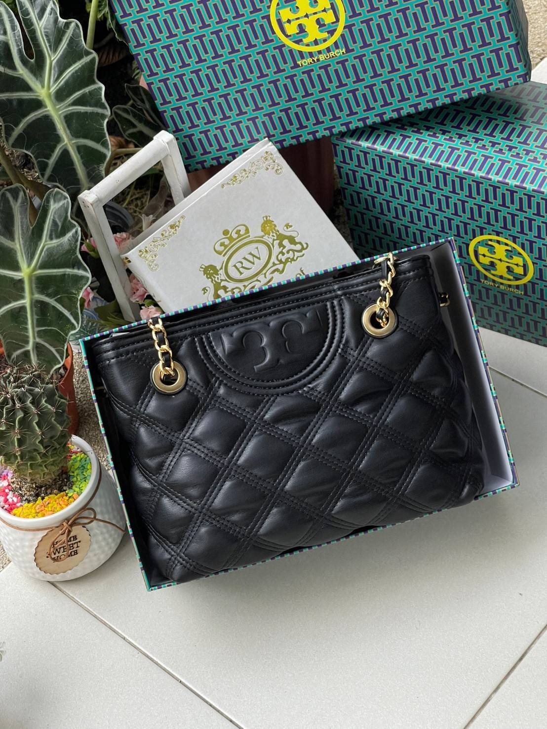 Tory Burch Fleming Soft Small Tote Bag เป็นกระเป๋าสะพายไหล่น่ารัก ๆ สักใบที่มีดีไซน์โดดเด่น สะดุดตา ใน Collection เรียกได้ว่าขายดีอันดับต้น ๆ ของแบรนด์ ใช้ได้ในลุคช์ทางการและกึ่งทางการ ดีเทลการตัดเย็บพิมพ์ลายนูนคู่กับแพทเทิร์นสี่เหลี่ยมทรงเพชร ที่ช่วยเพิ่