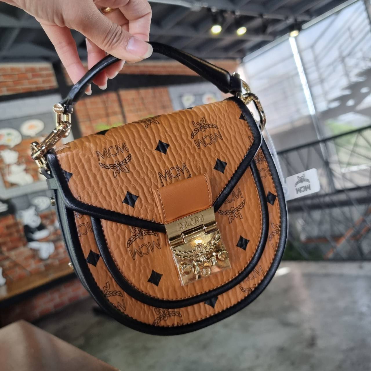 M.C.M MINI PATRICIA SHOULDER BAG IN VISETOS LEATHER BLOCK อัพเลเวลกระเป๋าของคุณด้วยไอเท็มนี้ไปเลยจ้า กระเป๋าสะพายทรง saddle ที่เก๋ไม่ซ้ำใคร ดีไซน์ขอบสีดำเพิ่มความยูนิค สวยสะดุดตา วัสดุหนังแคนวาสคุณภาพดี มาพร้อมสายสะพายหนังสีดำเรียบ และหูจับในตัว ทำให้ใช้ง