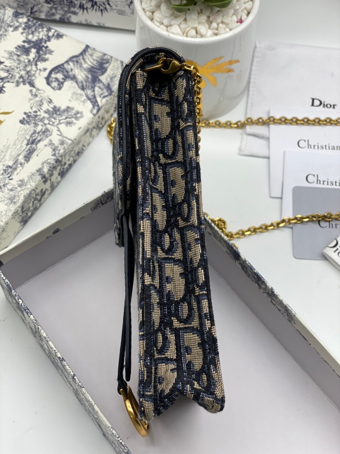 หนังแท้ DIOR PHONE BAG / DIOR PHONE HOLDER BAG กระเป๋าใส่โทรศัพท์เอกลักษณ์ของความหรู สายสะพายโซ่อะไหล่ทอง วัสดุหนังแท้และผ้า Jacquard อย่างดีสวยงามที่สุด ผสมผสานความสง่างามและคลาสสิกที่เข้ากับยุคสมัย ด้านหน้าโดดเด่นด้วยซิกเนเจอร์แบรนด์ เป็นอีกหนึ่งรุ่นที่