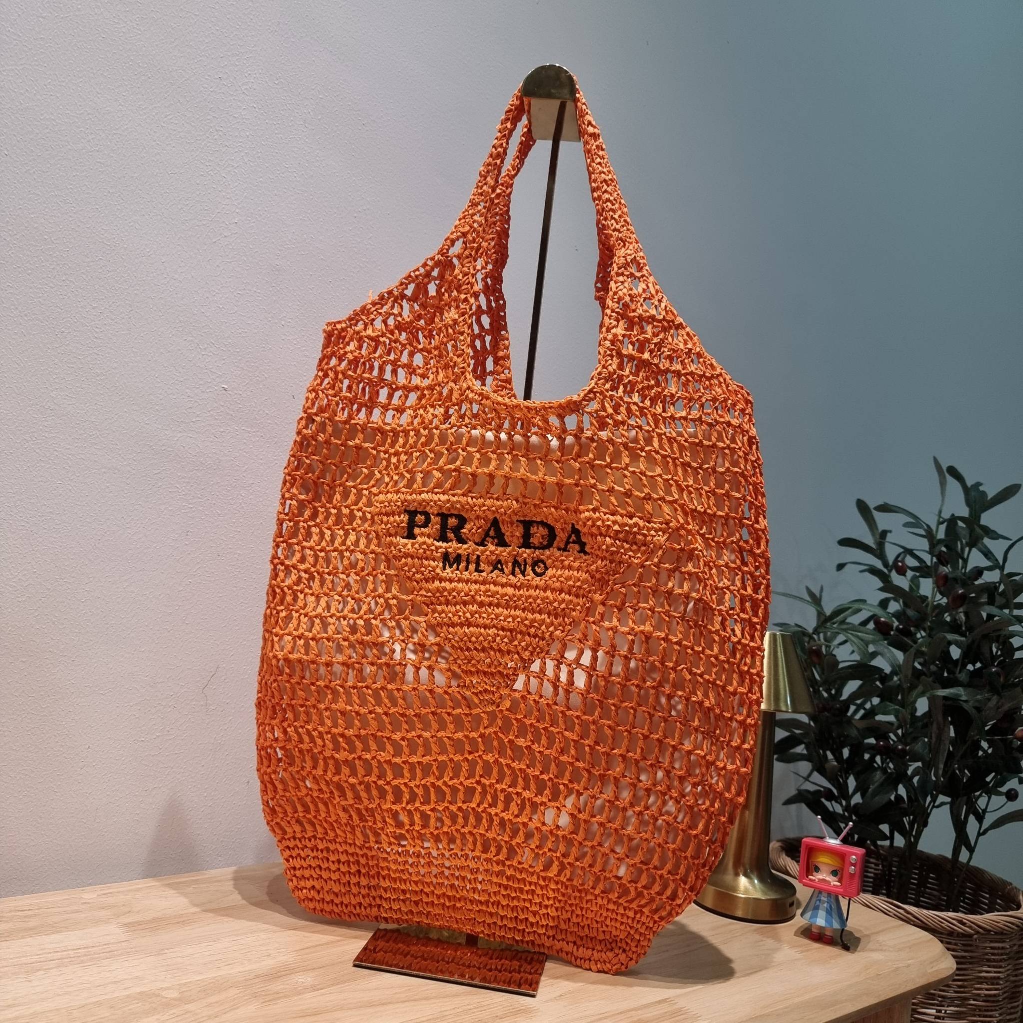 PRADA RAFFIA TOTE BAG สวยไม่ซ้ำใคร สไตล์บีช เหมาะมากกับการสะพายไปเที่ยวทะเล หรือจะใช้ในวันสบายๆก็ตอบโจทย์ กับกระเป๋าสะพายสานใบใหญ่ ตัวกระเป๋าเป็นวัสดุสังเคราห์จากธรรมชาติ สานทอเต็มใบออกมาเป็นลวดลายสวยงาม