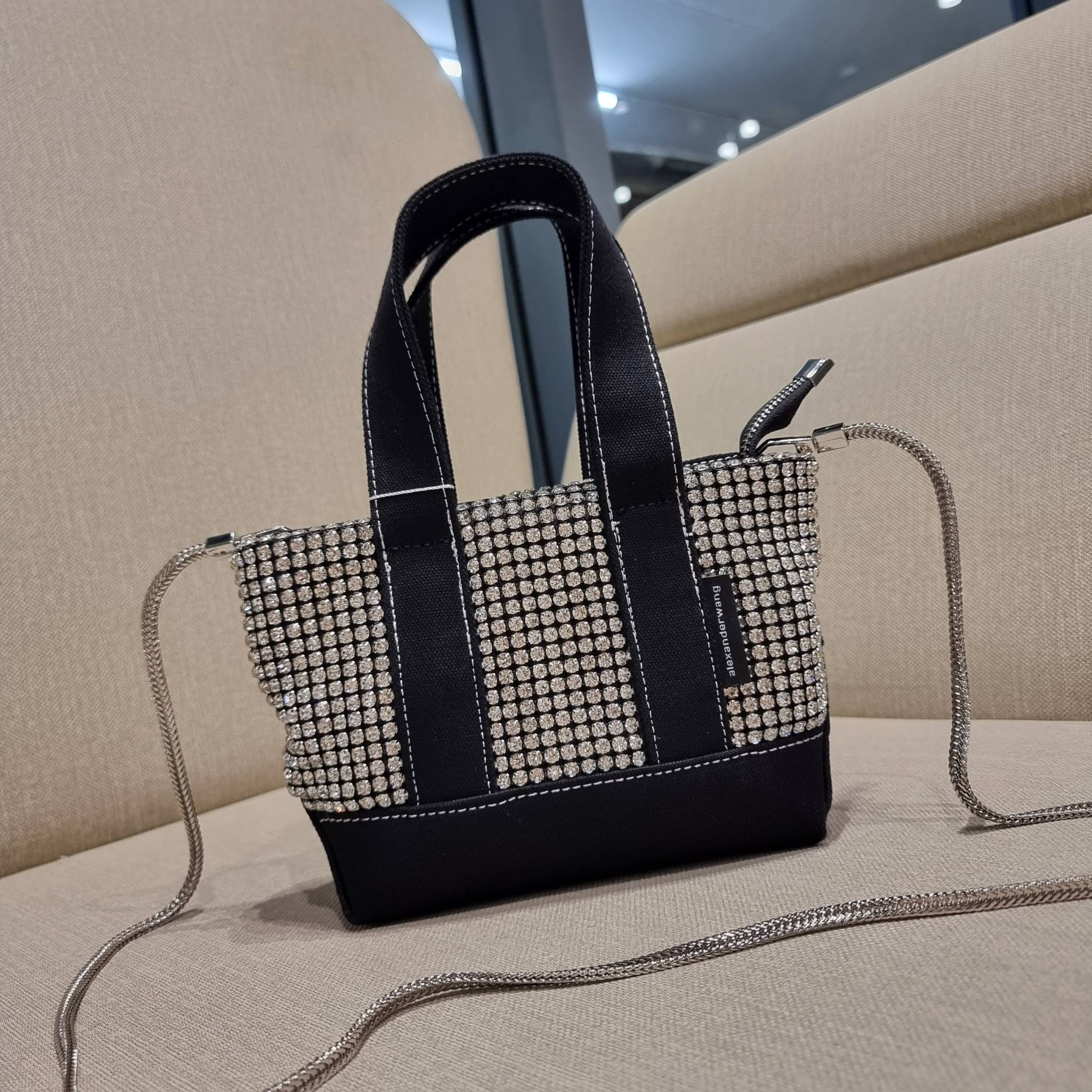 ALEXANDER WANG HANDBAG MINI TOTE WITH RHINESTONE กระเป๋าทรงมินิโท้ท น่ารักน่าเอ็นดู น่าใช้เหลือเกิน!! ด้วยความโดดเด่นเด่นของการตกแต่งพลอยเทียม ให้ดีเทลหรู ตัดสลับด้วยผ้าแคนวาส เพิ่มความทนทาน ลงตัวมากๆ และยังใช้งานง่ายด้วยหูจับในตัว เปิด-ปิดด้วยซิป ภายในเป