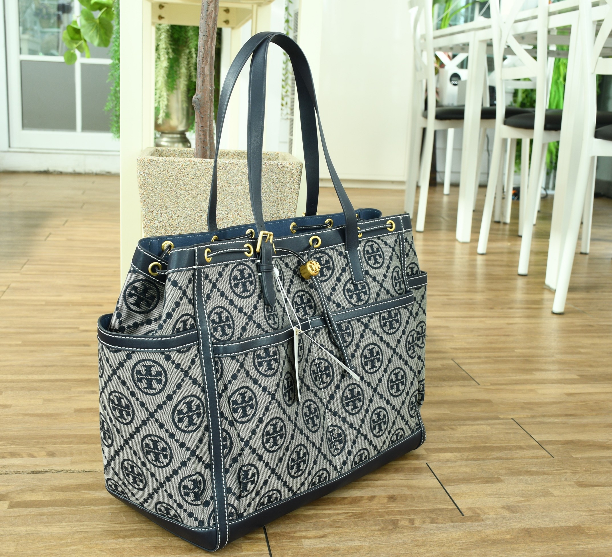 OUTLET 】TORY T MONOGRAM JACQUARD WFH TOTE กระเป๋าถือหรือสะพายไหล่ วัสดุ Canvas ปักษ์ลายแบรนด์ อะไหล่ทองสวยหรู น้ำหนักเบา จุของได้เยอะ ด้านหน้ามีกระเป๋าเล็ก2ช่อง ด้านหลัง2ช่อง ด้านในโล่ง มีช่องใหญ่1ช่อง ช่องเล็ก1ช่อง และอีก1ช่องซิป ใบใหญ่ Size XL ใส่เสื้อผ