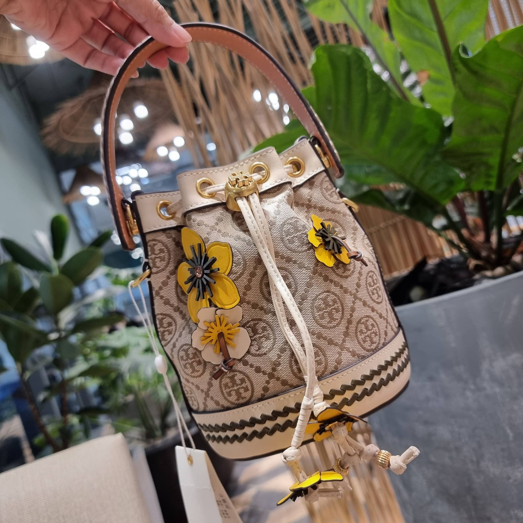 TORY BURCH MINI T MONOGRAM FLORAL BUCKET BAG คอลเลคชั่นใหม่ พร้อมเสิร์ฟความสวยให้ถึงบ้าน!! กระเป๋าบัคเก็ตทรงยอดนิยม ไซส์มินิ ดีไซน์ใหม่ล่าสุด สไตล์งานคราฟ มีลูกเล่นประดับดอกไม้กับตัวกระเป๋า และตัวรูดสาย วัสดุผ้า jacquard ตัดสลับหนังแท้ หูจับและขอบกระเป๋าต