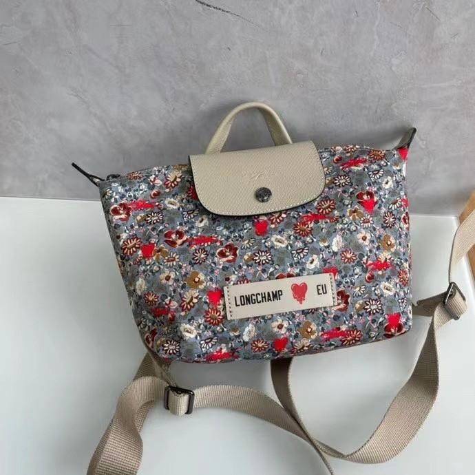 Longchamp X Eu Backpack กระเป๋าเป้สะพายหลังลายดอกๆไม้ วัสดุผ้าฝ้าย อะไหล่สีดำ กระเป๋าเป้แบบลำลองสำหรับสตรีซึ่งนำรูปทรงอันเป็นเอกลักษณ์ของ Le Pliage มาปรับใช้กับทุกสถานการณ์ อุปกรณ์เสริมที่ใช้งานได้จริงนี้มีสายรัดปรับระดับได้และที่จับช่วยให้ สะพายข้างหรือส