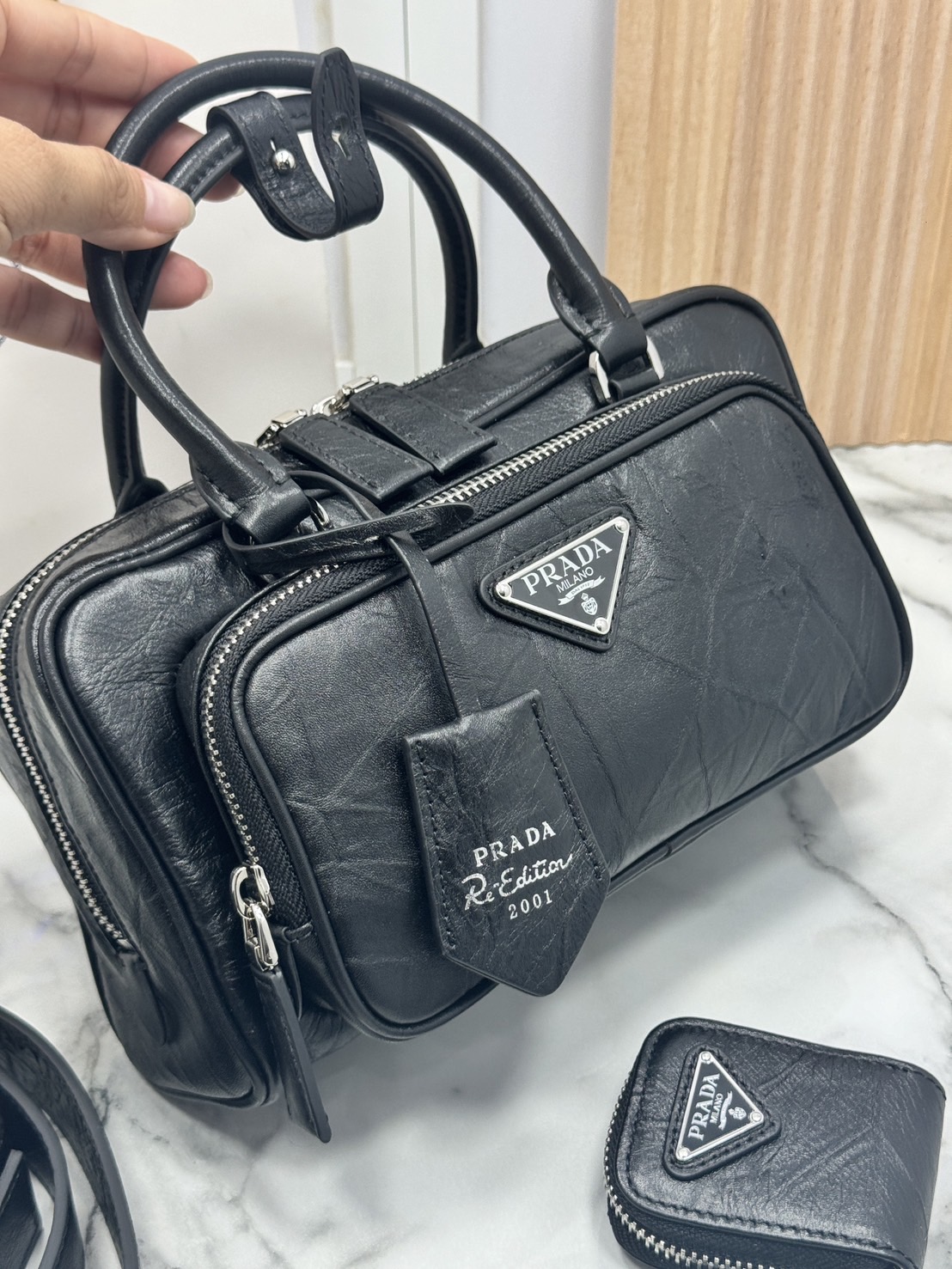 ORI หนังแท้ | Prada Antique nappa leather multi-pocket top-handle bag กระเป๋าสะพายทรง keepall มีช่องซิปด้านหน้าพร้อมหูจับ งานหนังยับดีไซน์เอฟเฟกต์เท็กซ์เจอร์ที่มีเสน่ห์สไตล์วินเทจ พร้อมทริกห้อยเพิ่มสไตล์สัมผัสที่โดดเด่นและร่วมสมัยยิ่งขึ้น