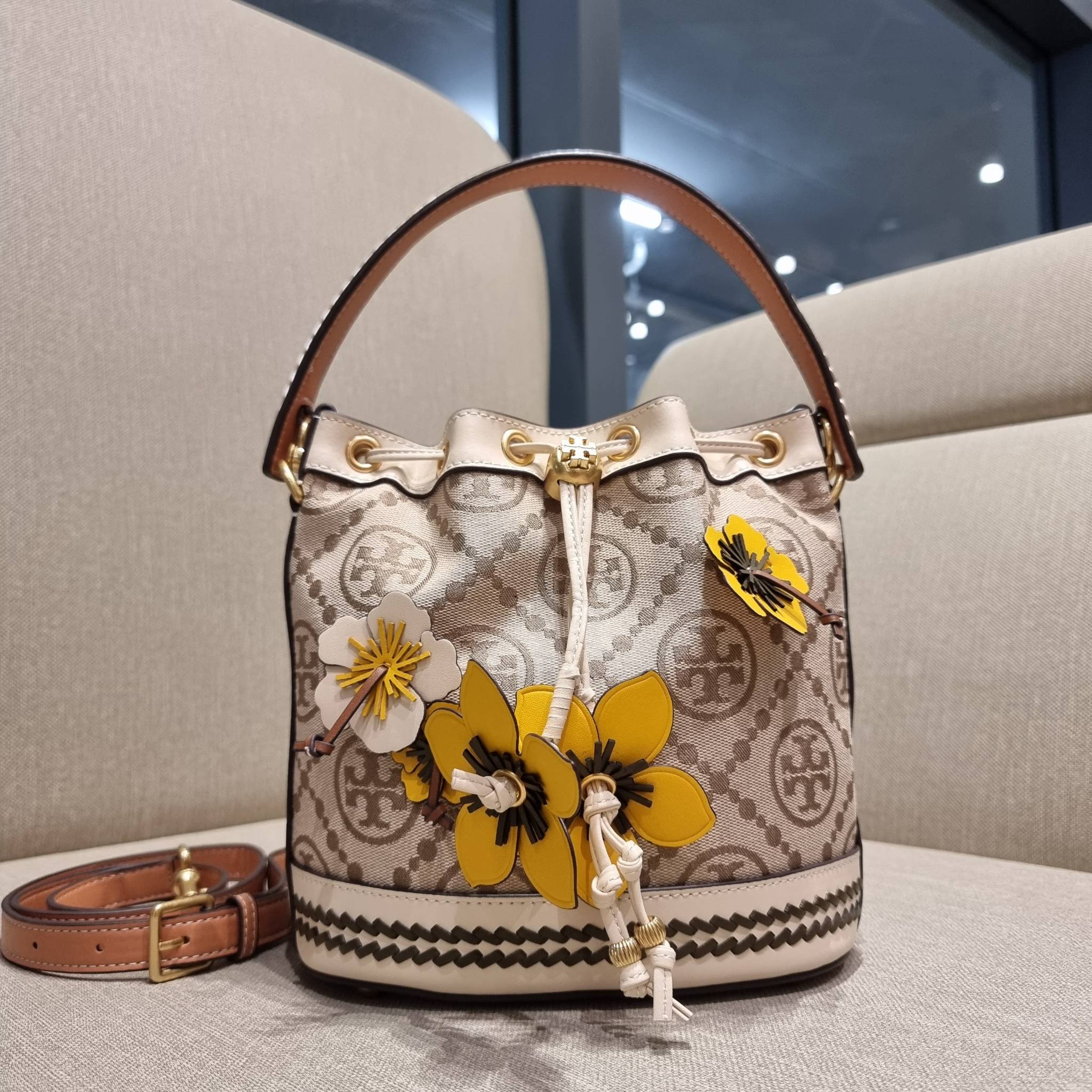 TORY BURCH T MONOGRAM FLORAL BUCKET BAG คอลเลคชั่นใหม่ พร้อมเสิร์ฟความสวยให้ถึงบ้าน!! กระเป๋าบัคเก็ตทรงยอดนิยม ดีไซน์ใหม่ล่าสุด สไตล์งานคราฟ มีลูกเล่นประดับดอกไม้กับตัวกระเป๋า และตัวรูดสาย วัสดุผ้า jacquard ตัดสลับหนังแท้ หูจับและขอบกระเป๋าตกแต่งลายสานสวย