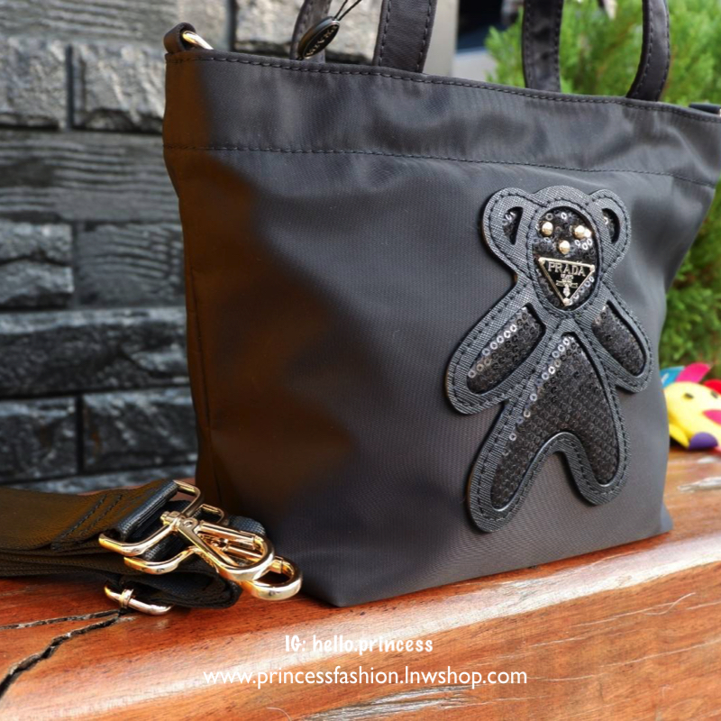 PRADA NYLON MINI TOTE BAG กระเป๋าสะพายขนาดมินิทรง TOTE พรีเมี่ยมกิ้ฟจากเคาน์เตอร์ต่างประเทศรุ่น Limited edition ที่ฮอตสุดๆในขณะนี้ วัสดุเป็น Nylon ตามแบบฉบับของแบรนด์ ขนาดมินิกำลังดี น้ำหนักเบา ด้านหน้าเป็นลายหมีปั๊กกลิ้ตเตอร์โลโก้แบรนด์อะไหล่ทองหรู ภายใน