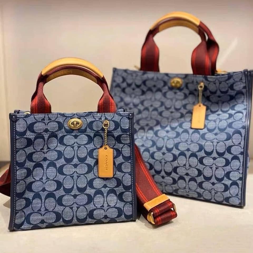 COACH Tote 34 In Signature Chambray หากคุณกำลังมองหากระเป๋าที่มีดีไซน์แปลกตา ไม่ค่อยเหมือนที่พบเห็นทั่วไป ต้องเป็นรุ่นนี้เลยค่ะ นอกจากจะผลิตจากผ้าแชมเบรย์ซึ่งมีน้ำหนักเบาแล้ว ยังให้สีสันคล้ายกับสียีนส์ สายสะพายและหูหิ้วสไตล์สปอร์ต ที่สำคัญยังมีหมุดปิดกระเ