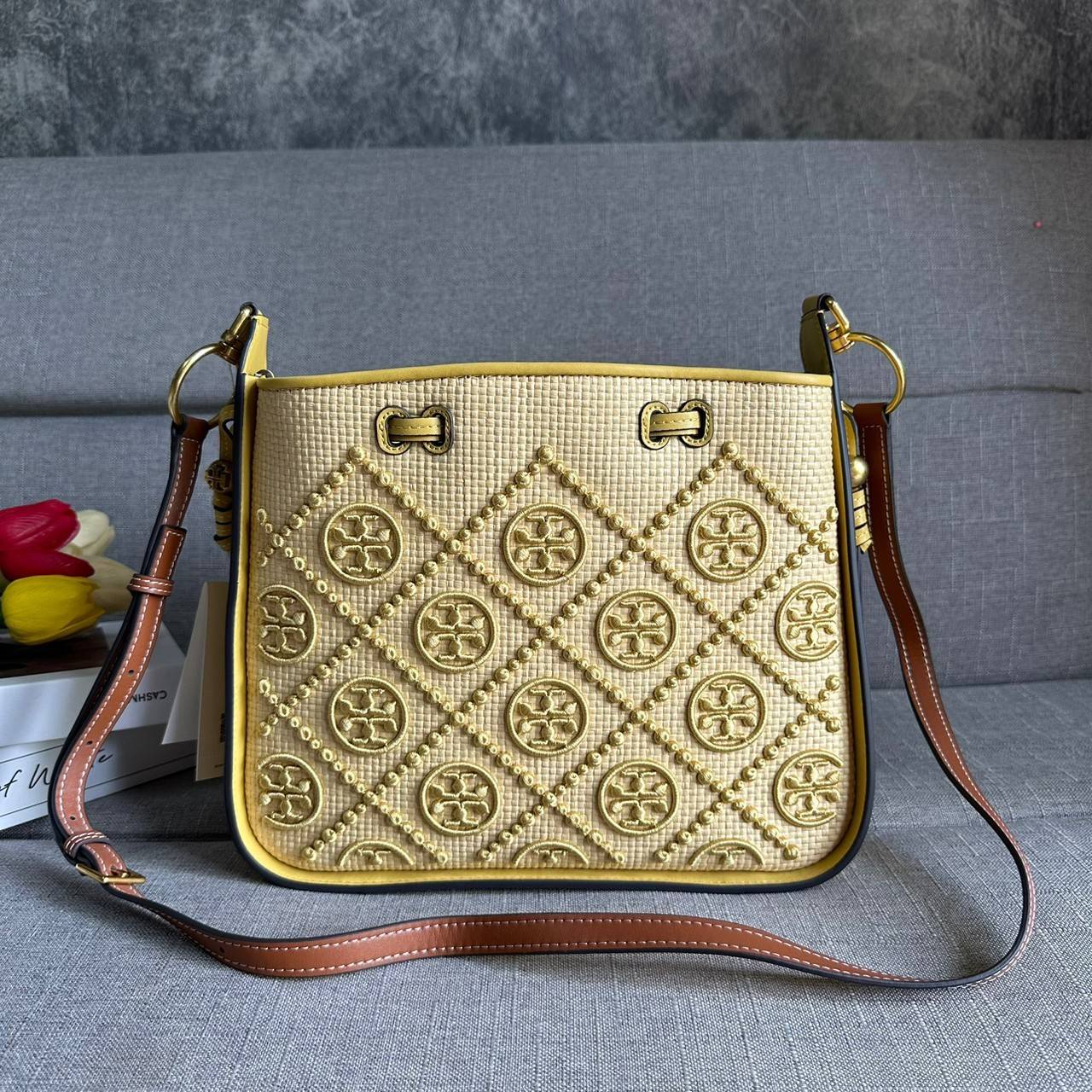 TORY BURCH T Monogram Straw Bell Bag กระเป๋าสะพายข้างรุ่นคลาสสิกที่ได้แรงบันดาลใจจากการควิลท์แบบดั้งเดิมของเพนซิลเวเนีย คอลเลกชันบ่งบอกถึงความมีสไตล์เหนือกาลเวลา รูปทรงเรียวโดดเด่น ปักทอลายแบรนด์อย่างสวยงาม เปิด ปิดด้วยเชือกรูด ด้านในช่องโล่งกว้าง ซับในผ้