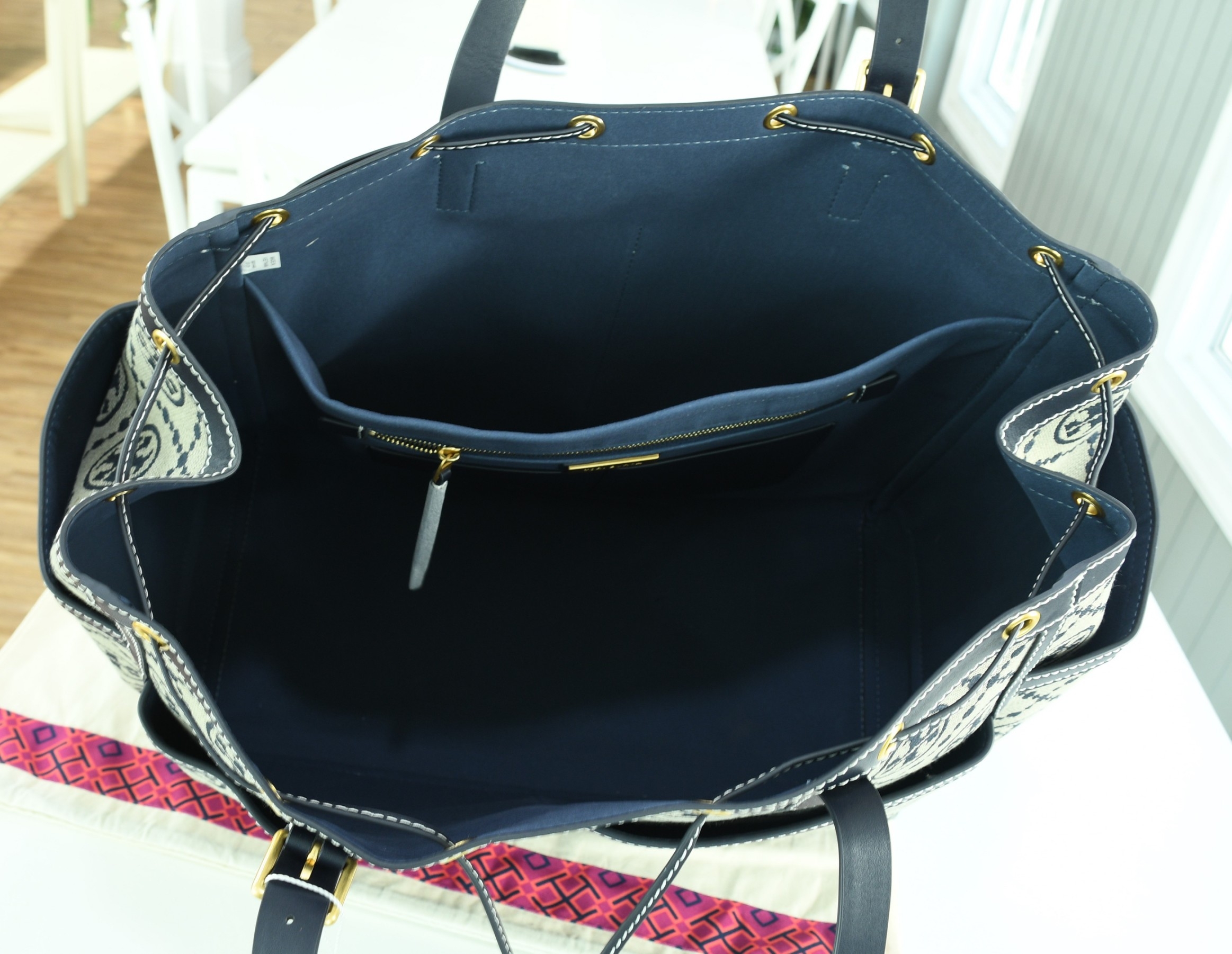 OUTLET 】TORY T MONOGRAM JACQUARD WFH TOTE กระเป๋าถือหรือสะพายไหล่ วัสดุ Canvas ปักษ์ลายแบรนด์ อะไหล่ทองสวยหรู น้ำหนักเบา จุของได้เยอะ ด้านหน้ามีกระเป๋าเล็ก2ช่อง ด้านหลัง2ช่อง ด้านในโล่ง มีช่องใหญ่1ช่อง ช่องเล็ก1ช่อง และอีก1ช่องซิป ใบใหญ่ Size XL ใส่เสื้อผ