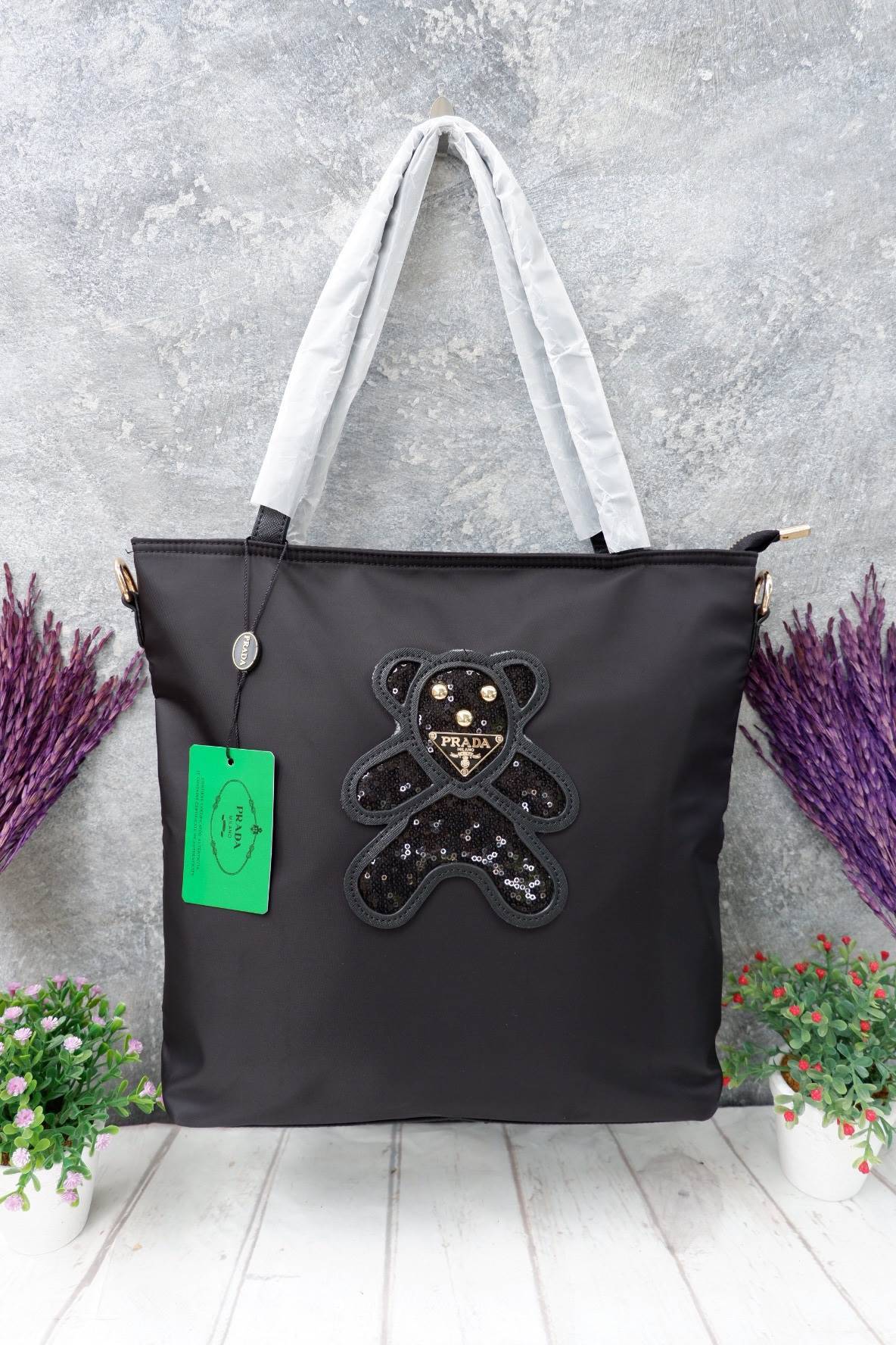 งานขายดีคะ ♡♡ กระเป๋าสะพาย ทรง TOTE จากแบรนด์ PRADA มาค่า ตัวกระเป๋าเป็น nylon ทั้งใบ สะพายเป็น shoulder bag หรือถือได้ค่ะ ด้านหน้าเป็นลายหมี ปักกลิ้ตเตอร์ + logo brand ใช้แล้วสวยมากๆ อะไหล่ทองหรูมาก จุของคุ้ม ใส่หนังสือ หรือ MacBook ได้ค้า 