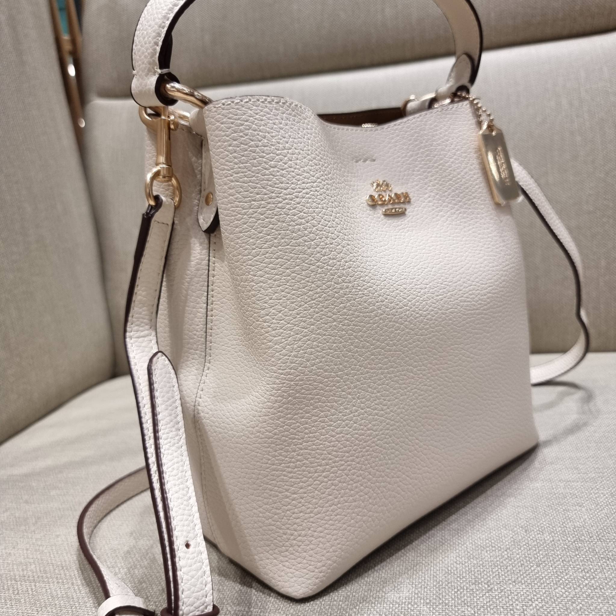 COACH 1011 SMALL TOWN BUCKET BAG รุ่นยอดนิยมใบเล็ก กระเป๋าทรงบัคเก็ต สีคลาสสิคเรียบหรู ตัดกับโลโก้สีทองดูโดดเด่น วัสดุหนัง pepble สวยคมทุกมุมจริงๆ!! เปิด-ปิดด้วยกระดุมแม่เหล็กทั้ง 2 ฝั่ง ภายในเป็นช่องโล่ง มาพร้อมสายสะพายปรับได้ตามตัว ขนาดใบนี้กำลังสวย สะพ