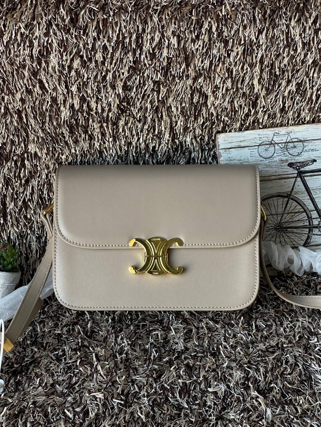 Celine MEDIUM TRIOMPHE BAG IN SHINY มีรูปทรงเป็นกล่องคล้ายกับกระเป๋า Classic Box แต่มีการออกแบบโลโก้ที่สะดุดตาแบบวินเทจ ด้วยดีไซน์ที่ดูโฉบเฉี่ยว แต่คงความคลาสสิคอย่างเต็มเปี่ยม ทำให้เป็นที่ดึงดูดความสนใจของสาวๆ สายสะพายสามารถปรับระดับได้ มีความคล่องตัวในก