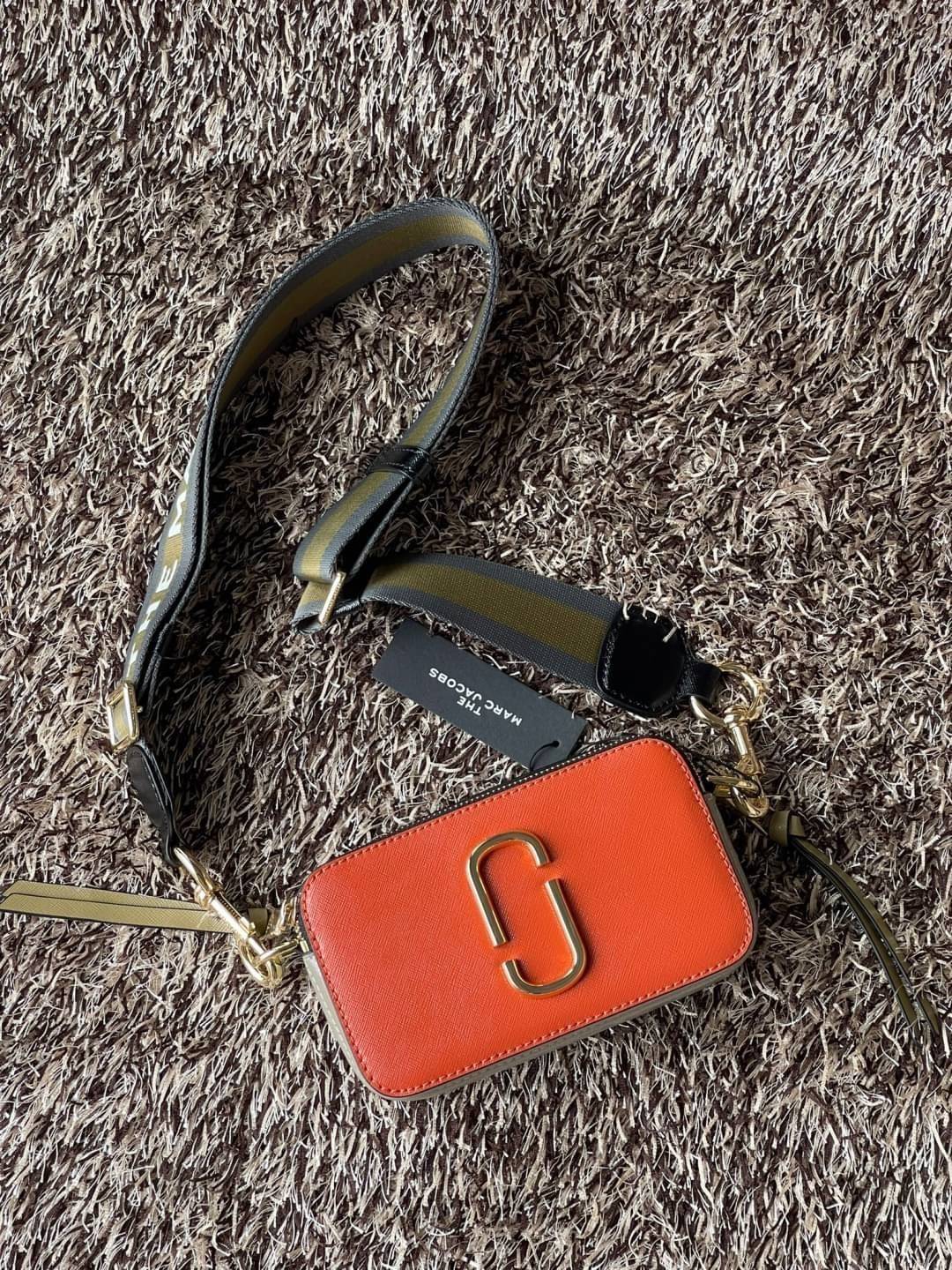 Marc Jacobs Snapshot Bag กระเป๋าแบรนด์ดังจากสัญชาติอเมริกัน นับได้ว่ารุ่นนี้เป็นรุ่นทรงฮิตเลยทีเดียว โดยด้านหน้ากระเป๋าจะเป็นโลโก้แบบโลหะที่เป็นสัญลักษณ์ของแบรนด์นี้ มาพร้อมสายสะพายที่จะสะพายยังไงก็ดูโดดเด่น เพราะขนาดใหญ่ที่สกรีนตัวอักษรโลโก้ ในรูปแบบต่าง