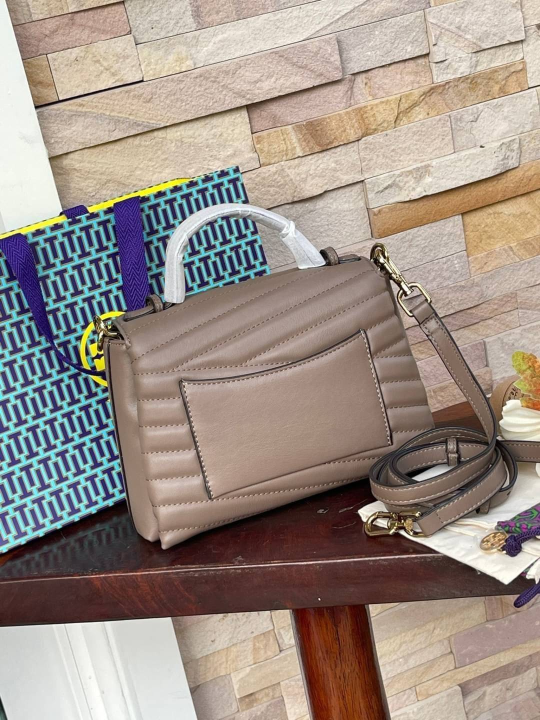 TORY BURCH Kira Chevron Top-handle Satchel กระเป๋าหนังแกะ สัมผัสนุ่มควบคู่กับดีไซน์อันเป็นเอกลักษณ์ กระเป๋าถือทรงสวยที่มีดีไซน์อันเป็นเอกลักษณ์ไม่เหมือนกับที่ไหน ด้วยการตัดเย็บหนังแกะแสนนุ่มแบบลายบุสองชั้น เพิ่มมูลค่าด้วยสายสะพายที่ทำจากโลหะสีทอง อีกทั้งย