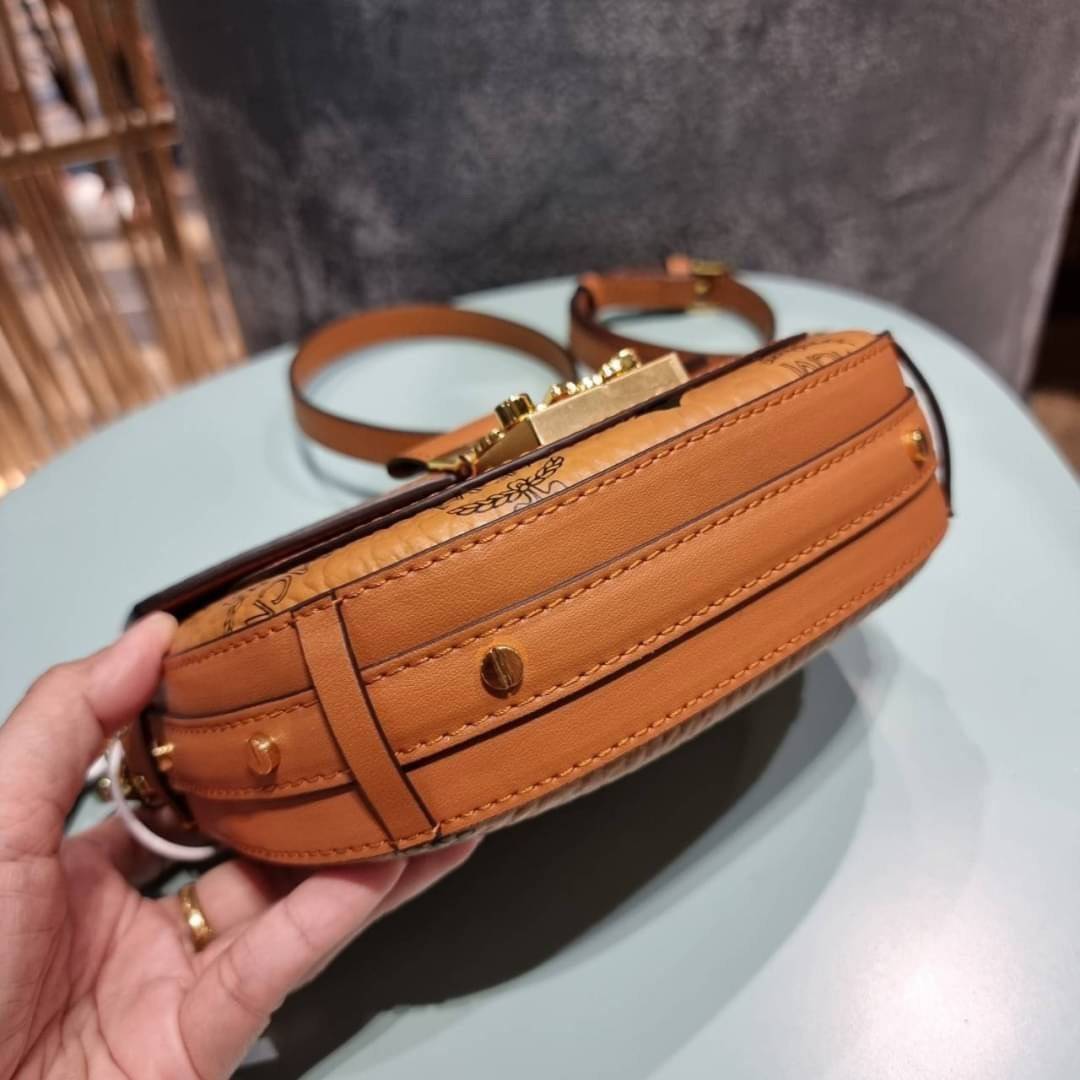 M.C.M MINI PATRICIA CROSSBODY IN VISETOS กระเป๋าสะพายไซส์มินิ แรงดีไม่มีตกน้า คอลเลคชั่นนี้ดีไซน์แปลกใหม่ ทรงโค้งมน สวยหรู ด้านข้างตกแต่งหมุดทองรอบใบ วัสดุตัวกระเป๋าเป็นหนังแคนวาสคุณภาพดี ภายในเป็นหนังกลับสีส้มโดดเด่นเป็นเอกลักษณ์ มีช่องใส่บัตรแยกให้ เปิด